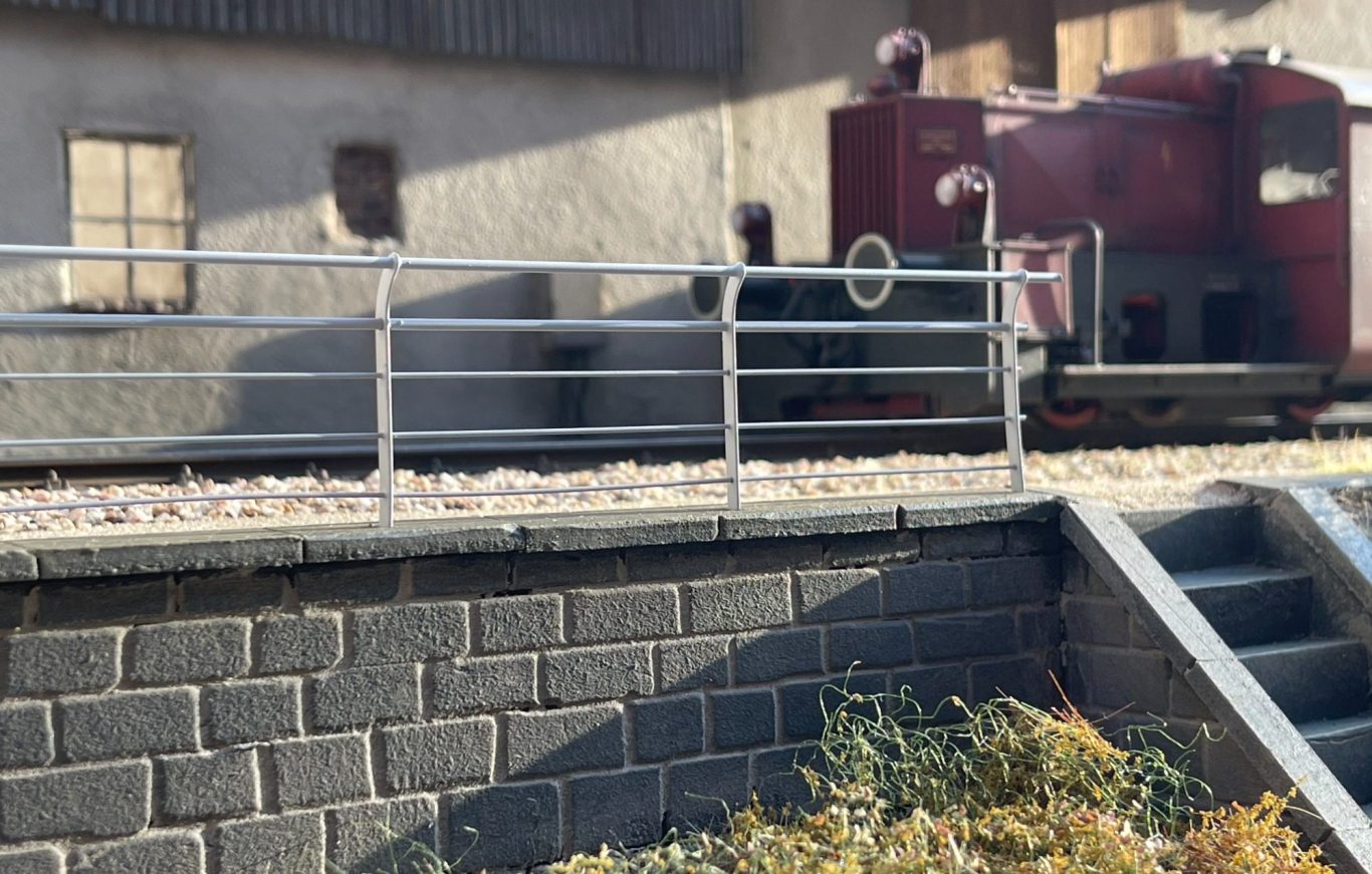 Graues Geländer des Typs Chamues von Becker&Sohn Modellbau in Spur1 vor einem Industriehintegrund